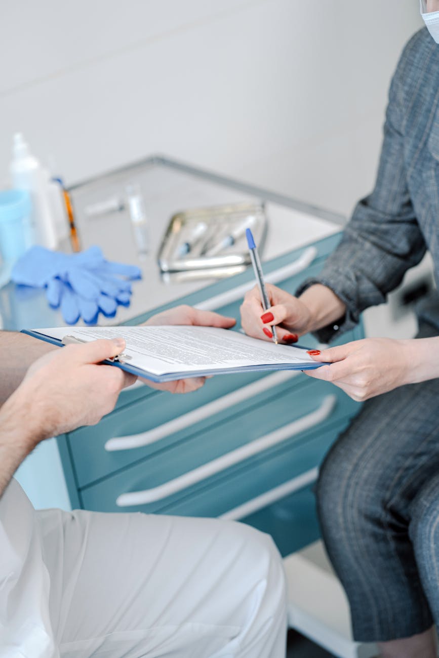 Patient signing healthcare agreement in doctor's office, focus on hands and document exchange.
