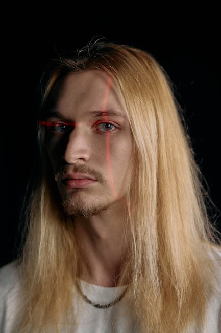 Studio portrait of a man illuminated by laser lines against a black background.