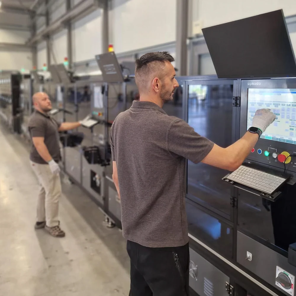 Man standing and operating a Apkudo automated robotic line