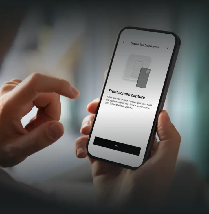 Hand holding a smartphone displaying a screen titled 'Device Self Diagnostics' with instructions for front screen capture and a 'Yes' button.