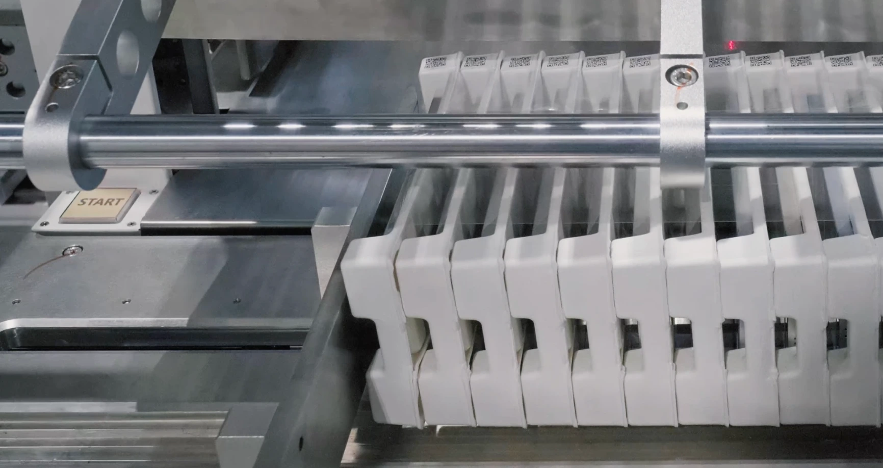 Close-up of a mechanical component with white parts lined up and a metal rod above them.