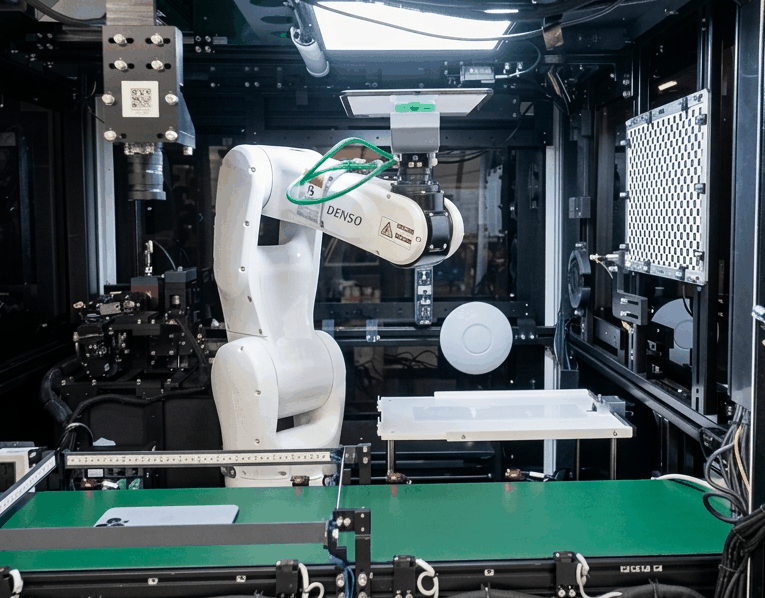 Robotic arm and inspection cameras inside the BackBot unit, positioning a device over the test bed