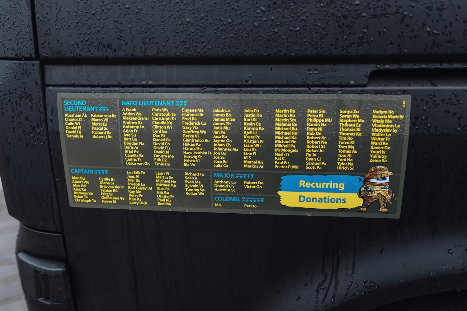  Black NAFO Truck, displaying a large list of the names of the recurring donors names of ranks of recurring donors of the 69th Sniffing Brigade Second Lieutenant, NAFO Lieutenant Captain, Major and Colonel