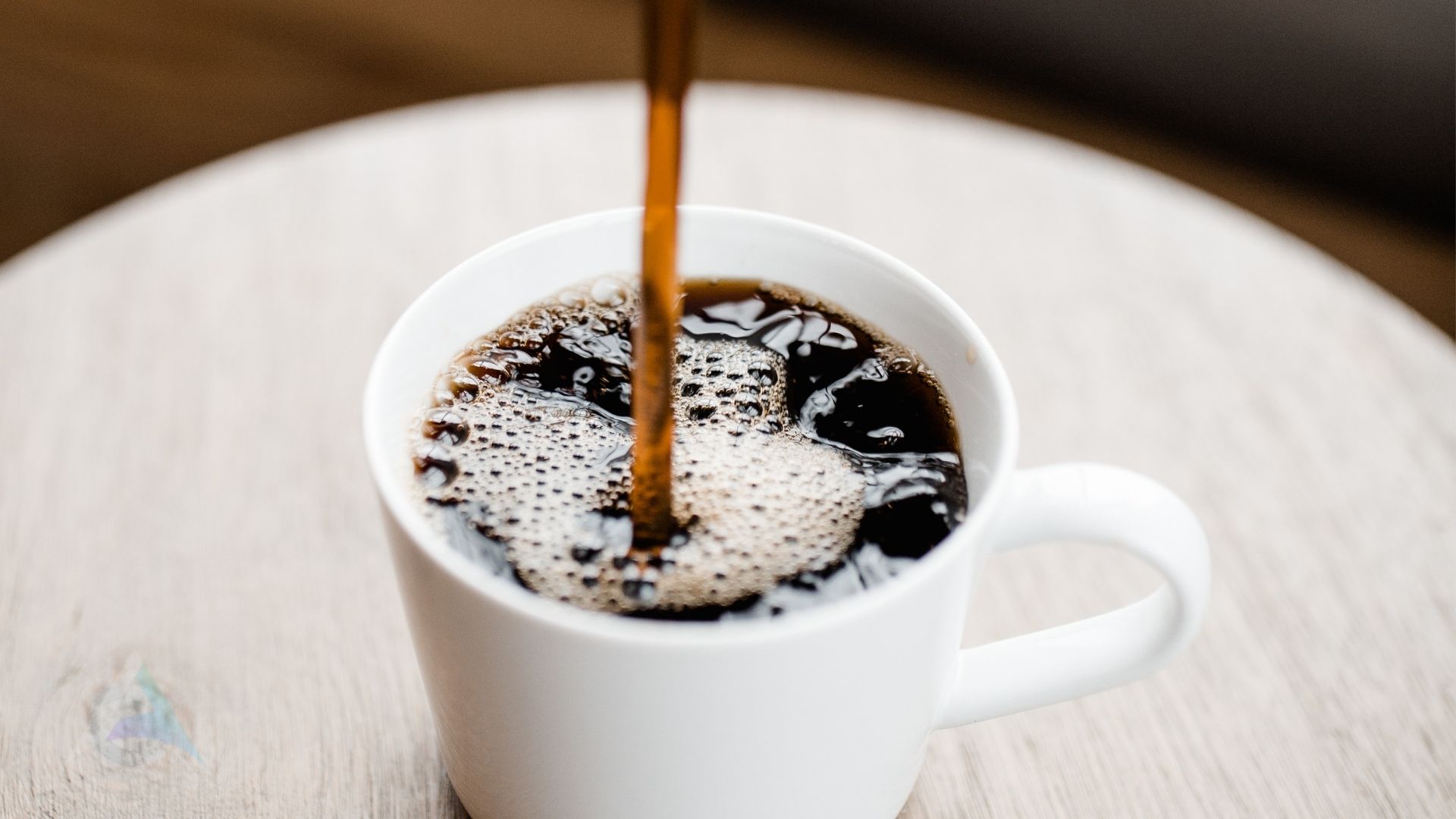 A cup of black coffee beside a glass of water representing mindful caffeine consumption for nervous system health and migraine prevention