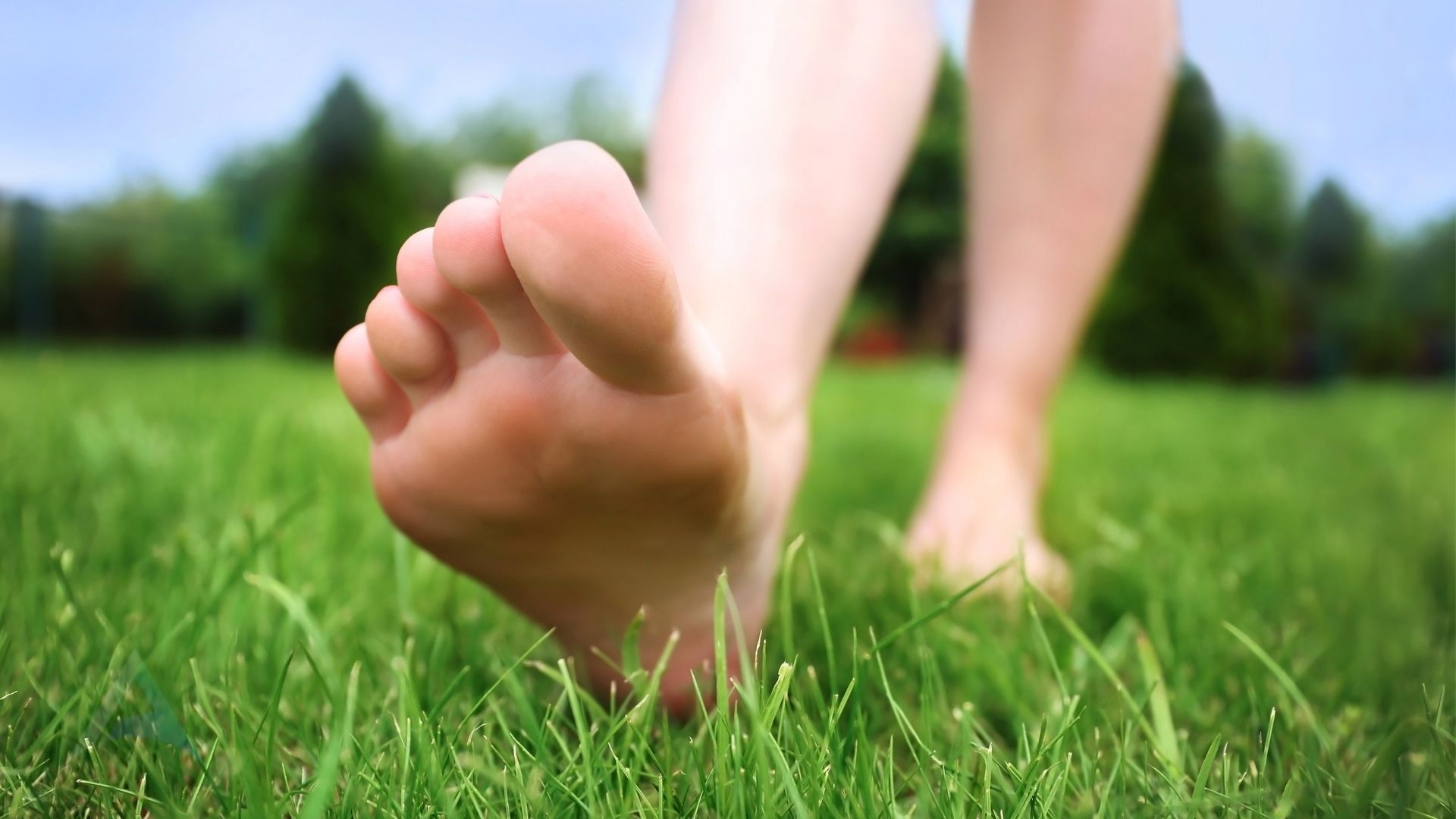 Bare feet on grass with a yoga mat representing natural stress reduction through grounding and movement to support nervous system health