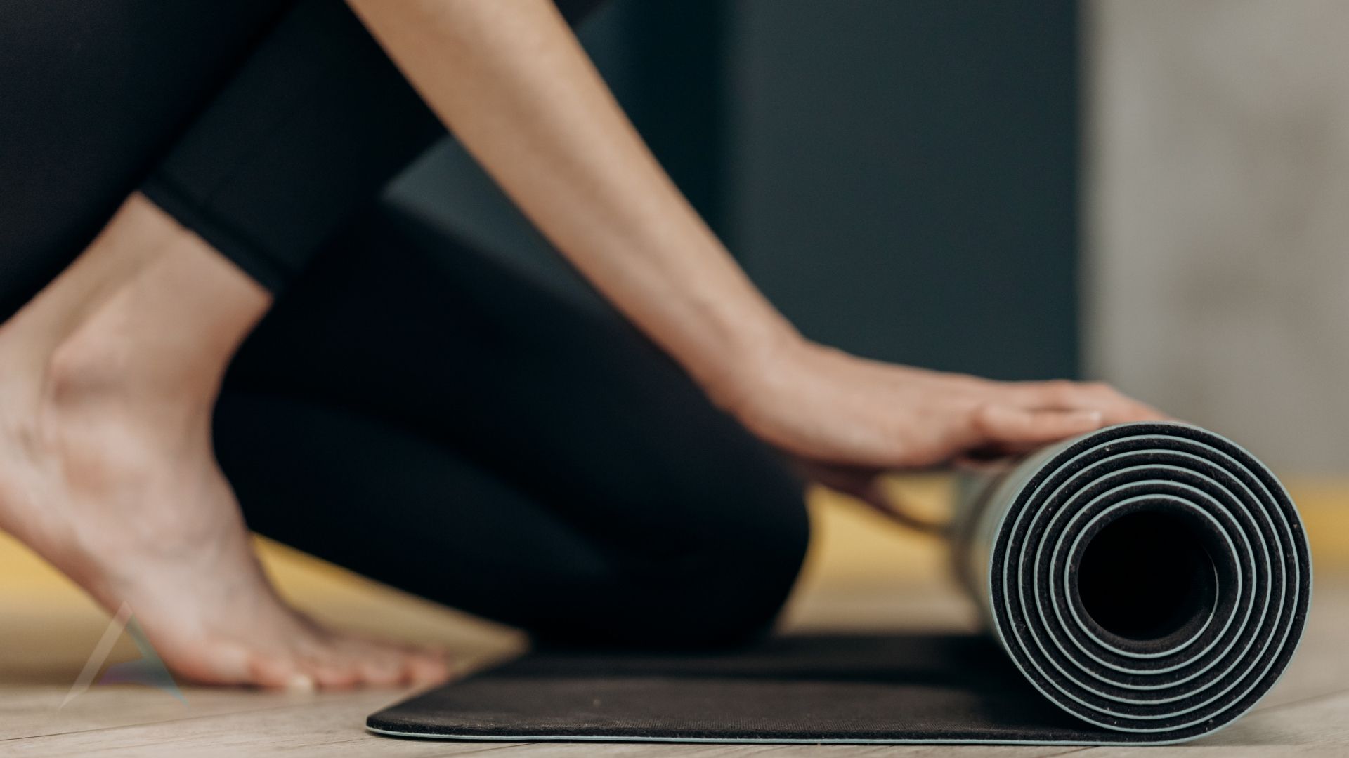 Rolled yoga mat, towel, and glass of water in a sunlit room, representing gentle movement and self-care for fibromyalgia