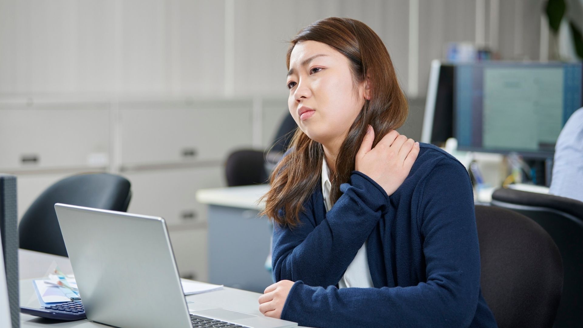 Person pressing the base of the skull and upper neck, illustrating a cervicogenic headache that starts in the neck