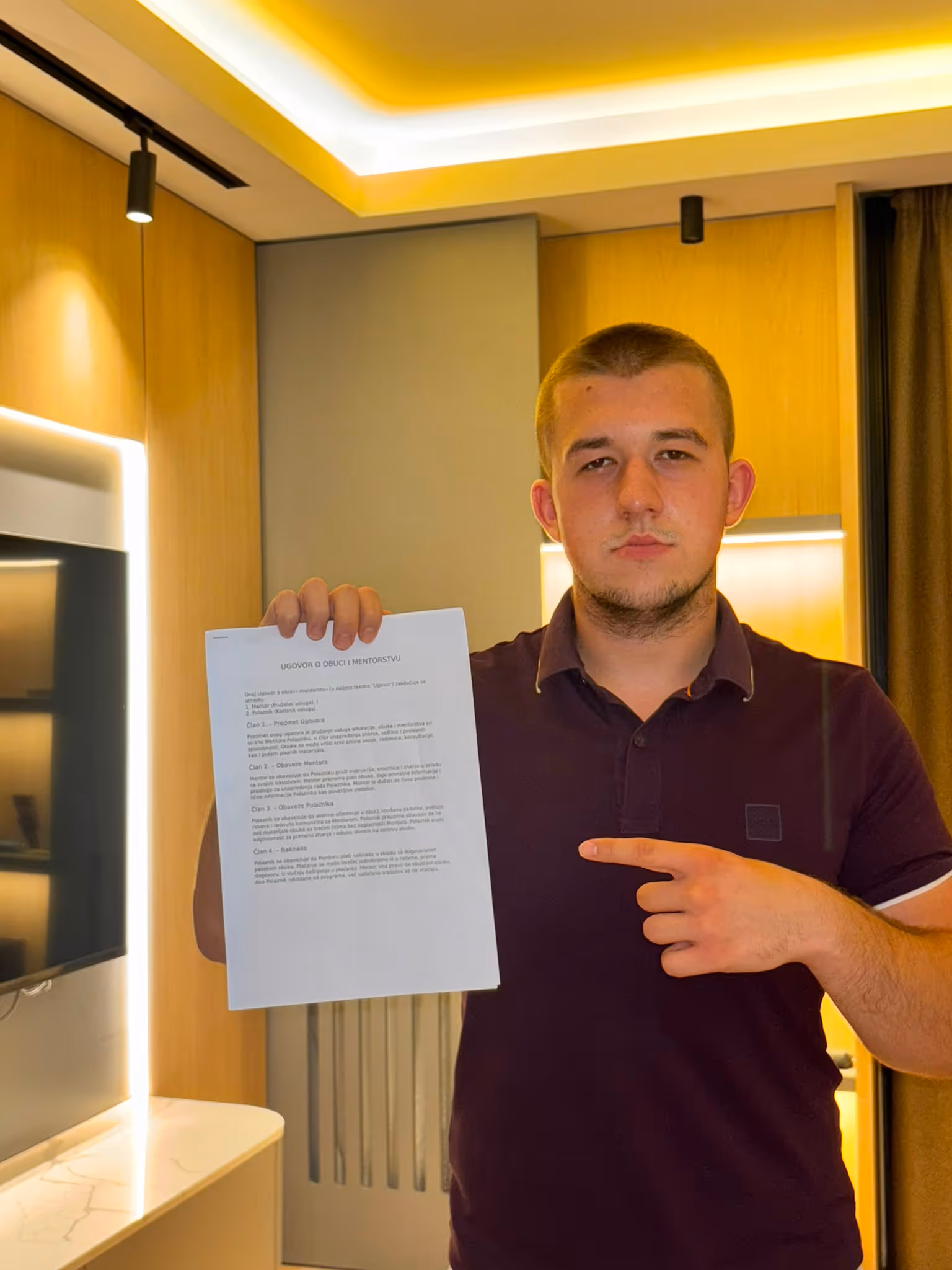 Muškarac pokazuje papir sa ugovorom o obuci i mentorstvu u modernoj sobi.