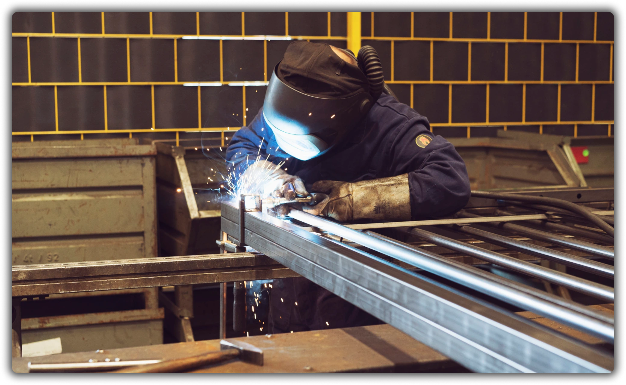 Soudeur dans une usine de De La Fontaine fabriquant une structure métallique pour portes et cadres en acier.