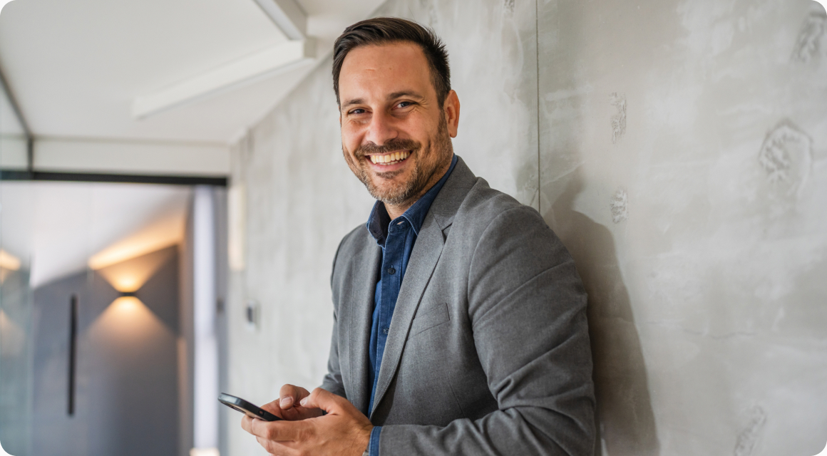 Smiling broker holding a phone in a modern office