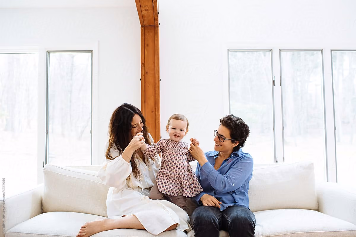 Two parents playing with their toddler on a sofa