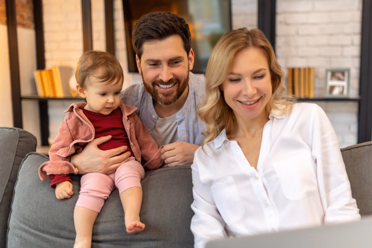 Two parents playing with their toddler on a sofa