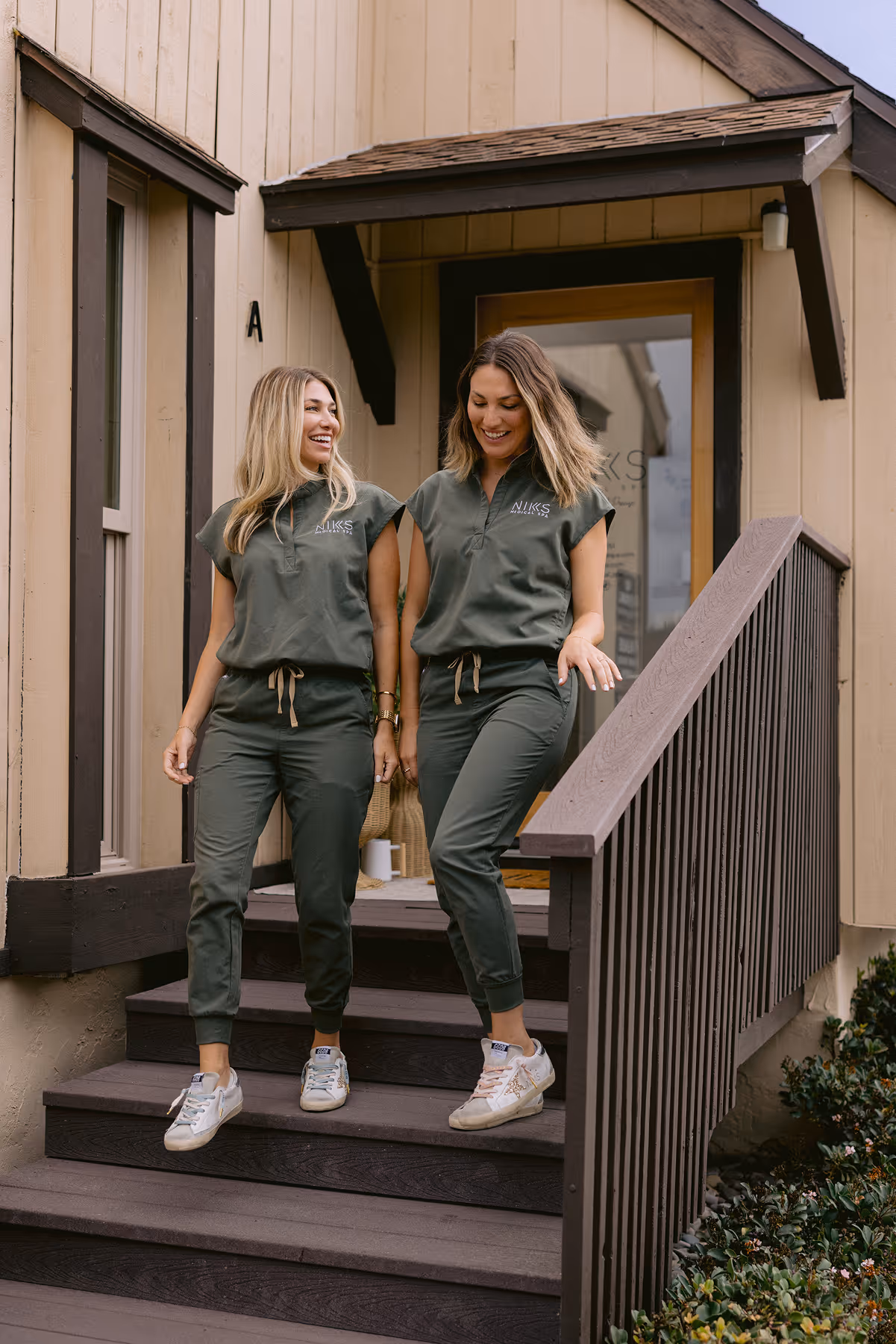 Two women standing on the steps of a house.