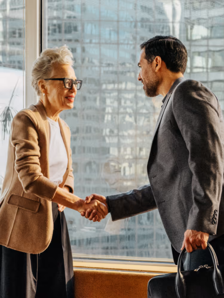 Image of coworkers shaking hands over desk