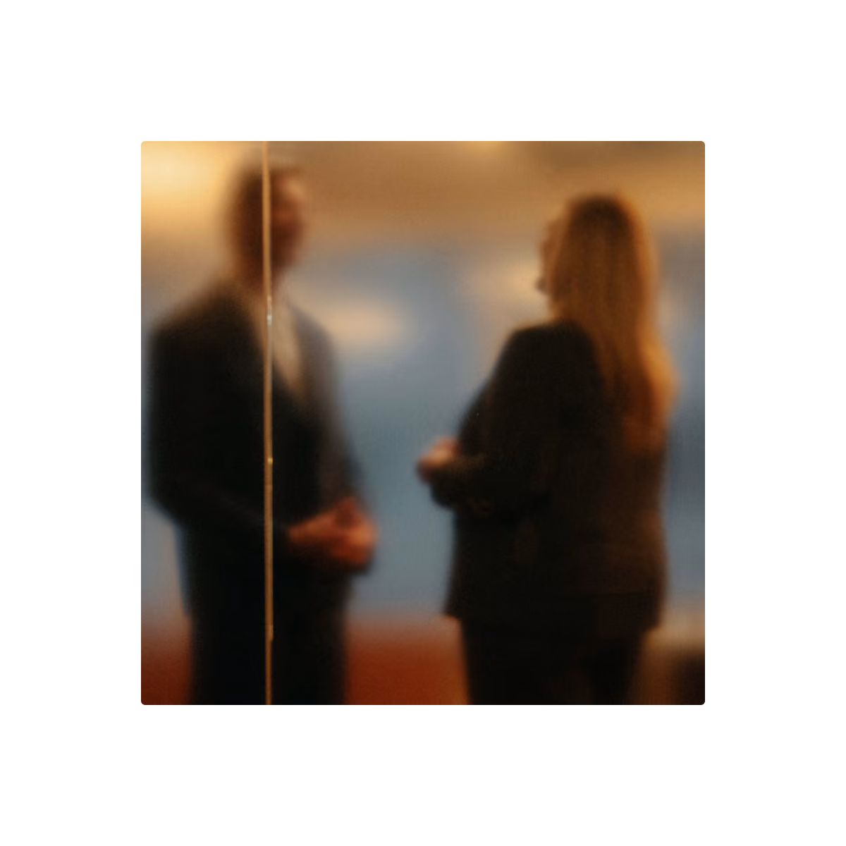 A blurred image showing two people facing each other, likely engaged in conversation, with a vertical line dividing the scene.