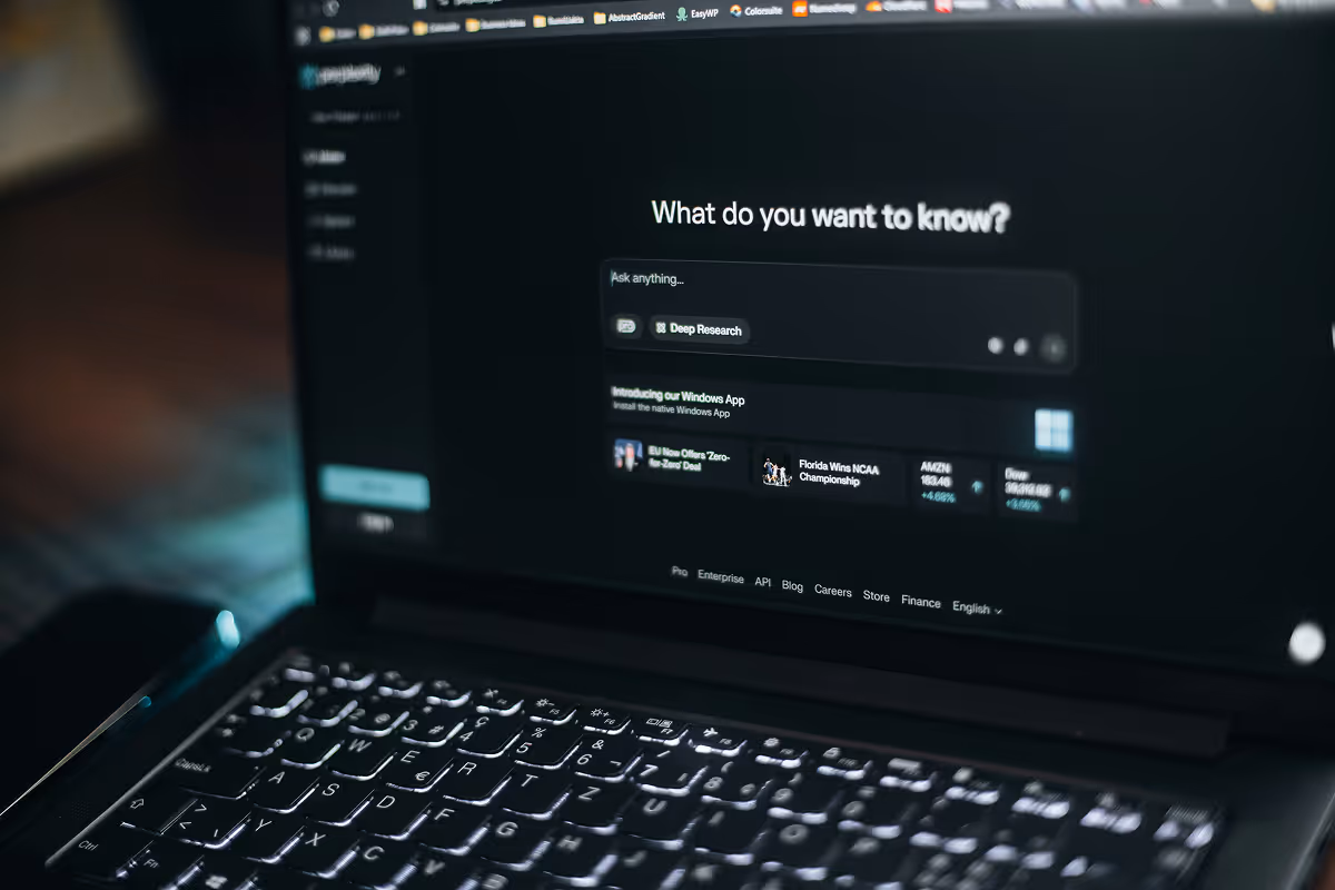 Close-up of laptop keyboard and screen showing a dark themed search interface with 'What do you want to know?' prompt.