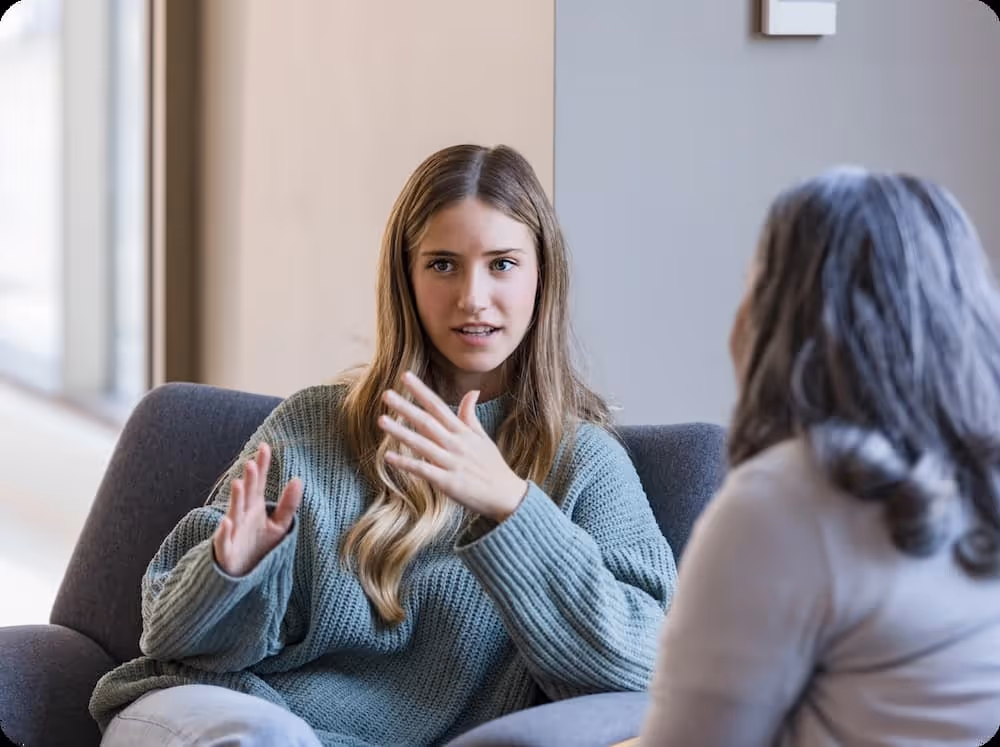 a woman sitting on a couch talking to another woman