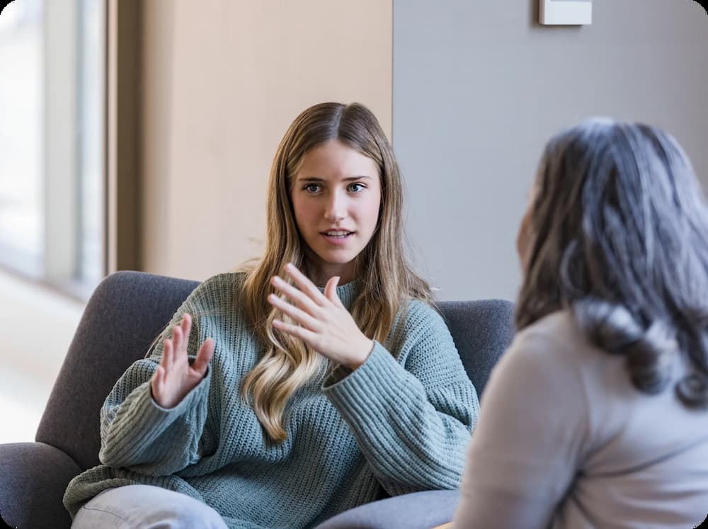 a woman sitting on a couch talking to another woman