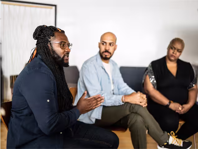 a group of people sitting on top of a couch during group therapy.