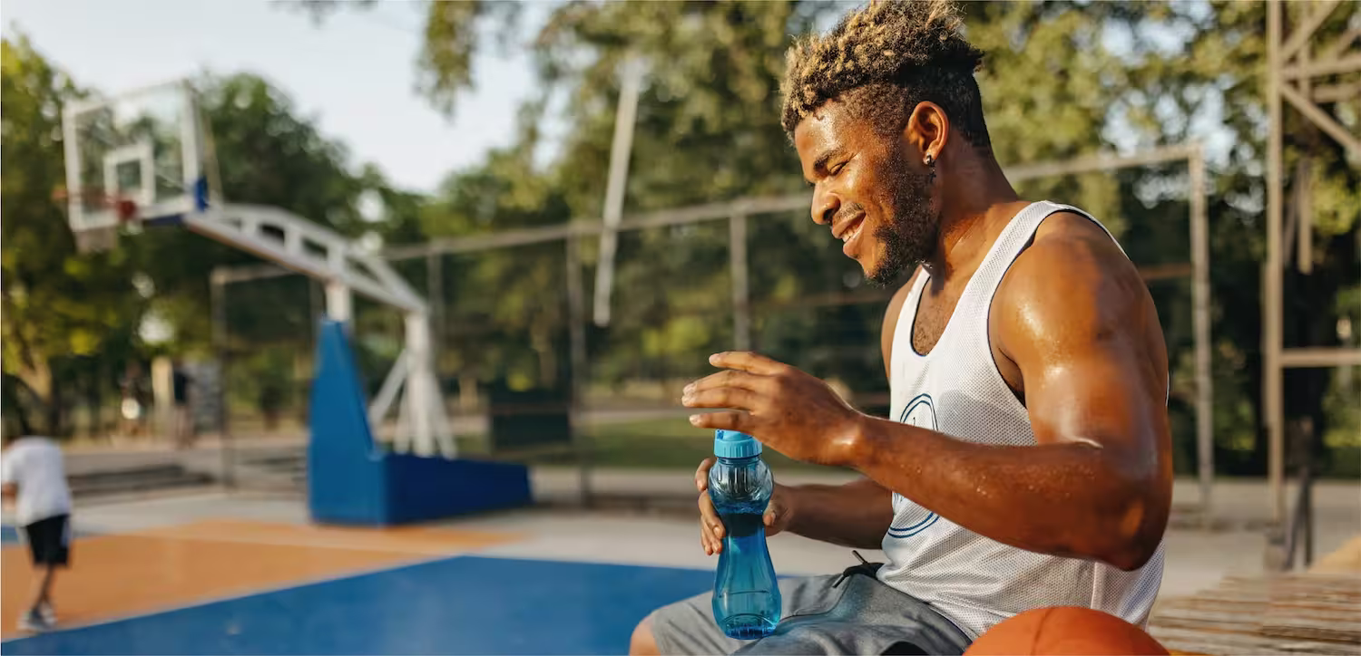 a man sitting on a basketball court holding a bottle of water