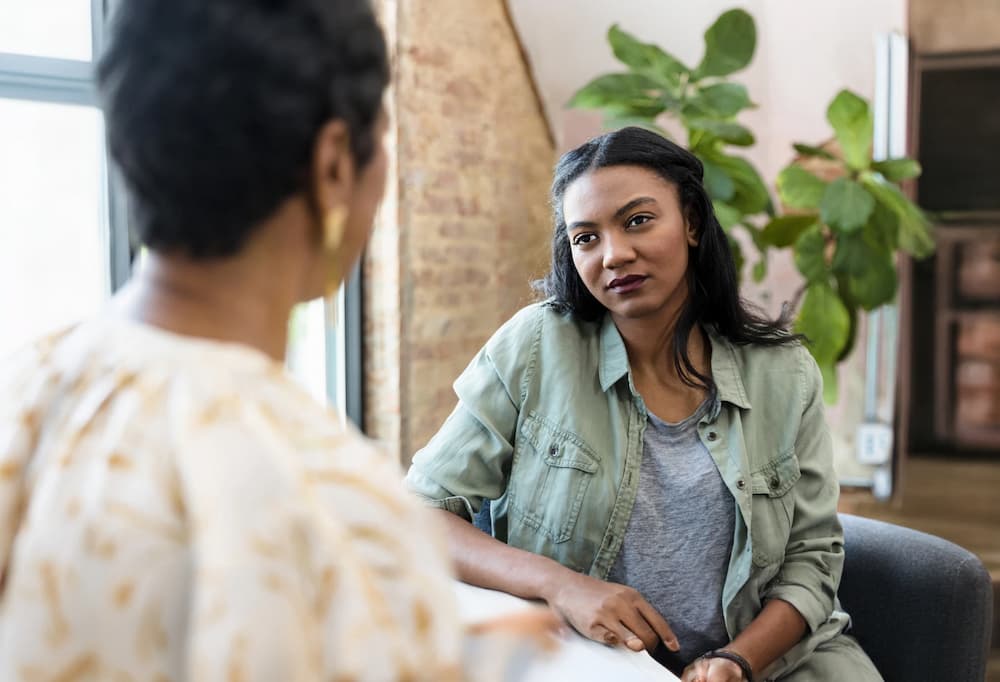 A woman with a green shirt sitting at a table during therapy.