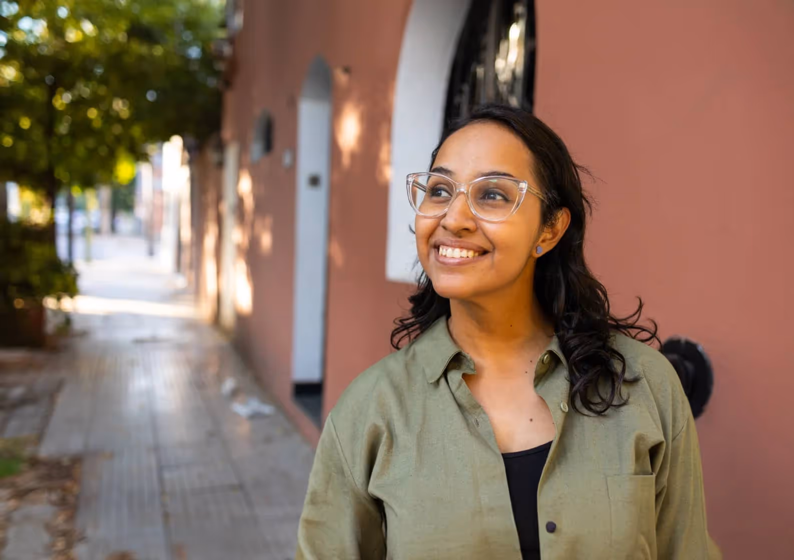A woman wearing glasses standing in front of a building.
