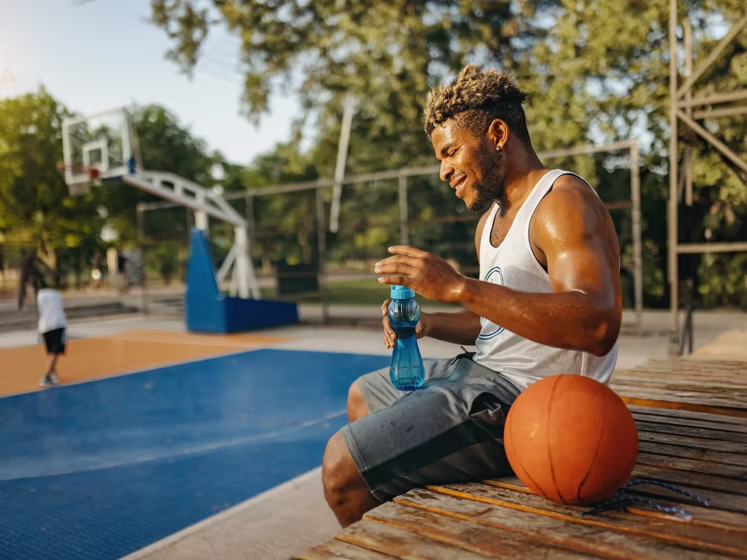 A man sitting on a bench with a blue water bottle.