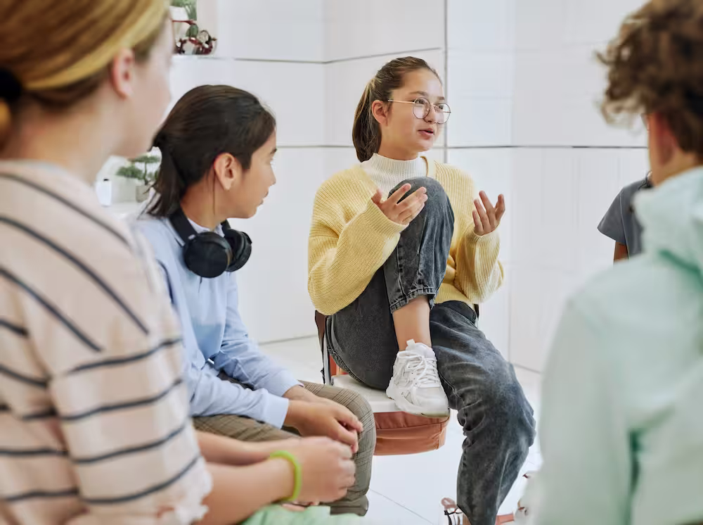 A group of young people sitting around each other at group therapy.