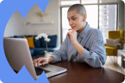 Woman with blue shirt sitting at table on her computer.