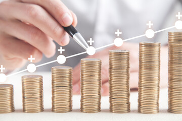 Male hand drawing growth graph. Coins on white table
