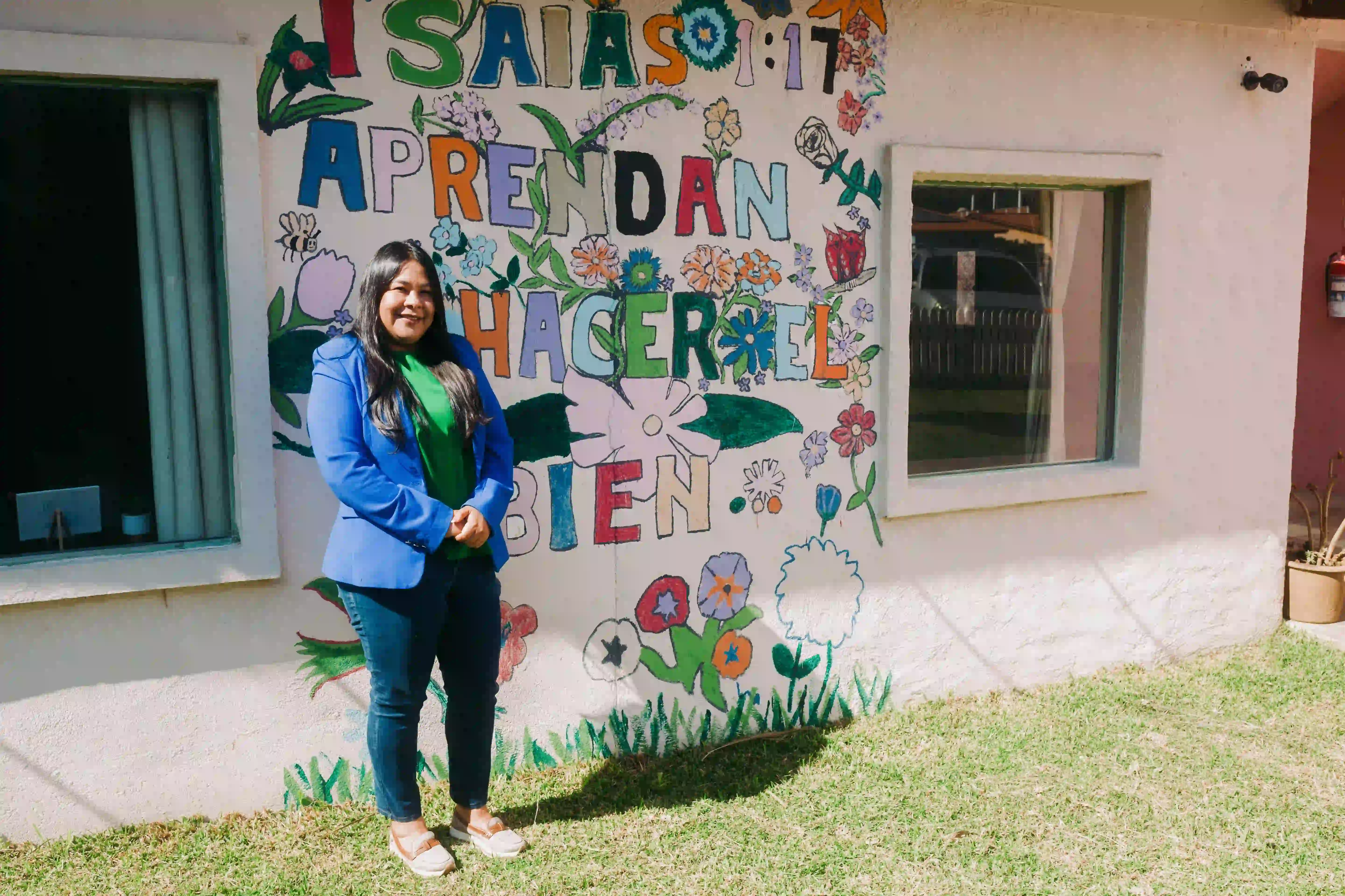 Tia Vicky standing outside of a mural at the Oasis campus