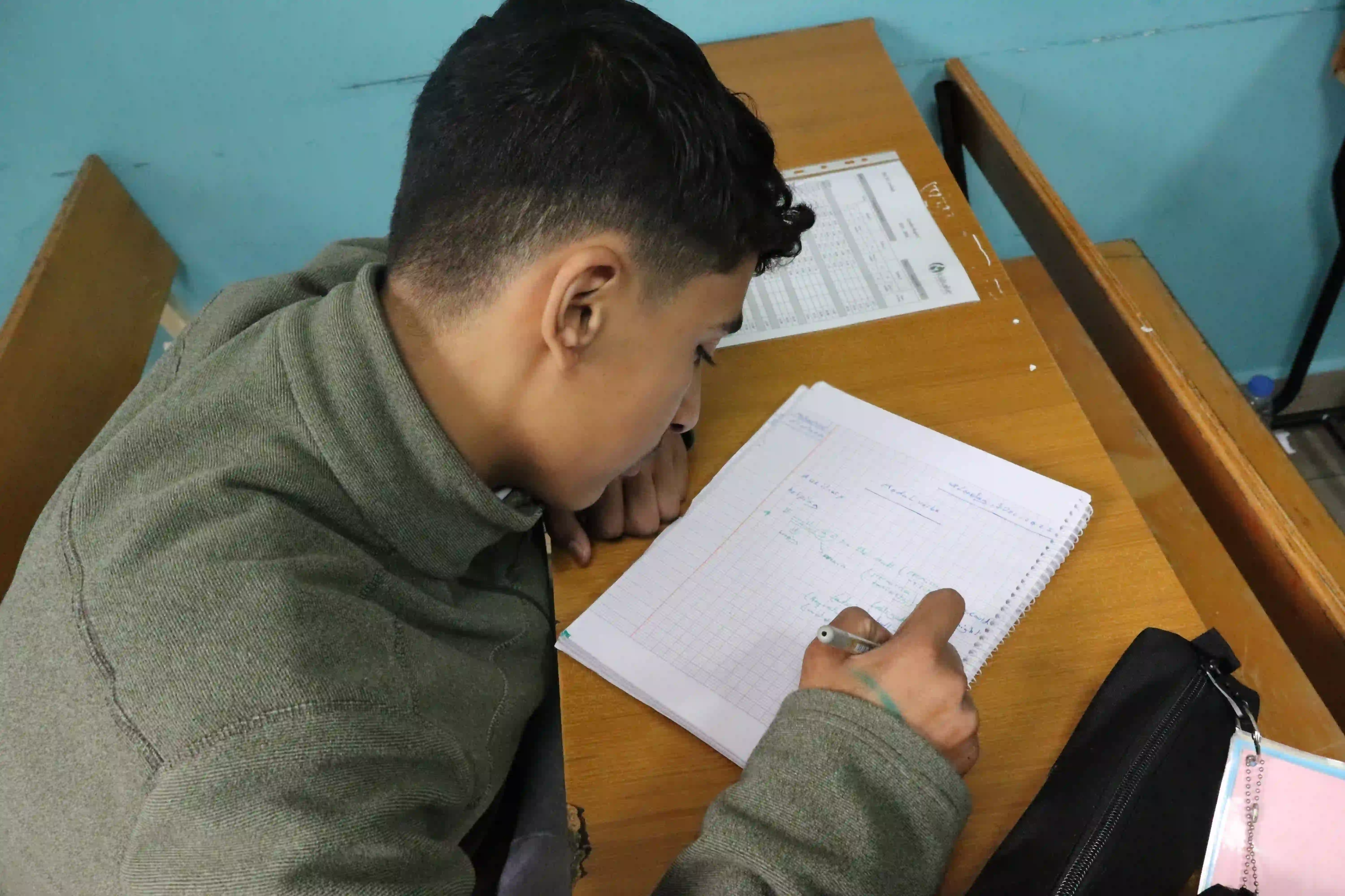 Samir sitting at his desk at Kids Alive Lebanon’s Dar El Awlad School, working on an assignment.