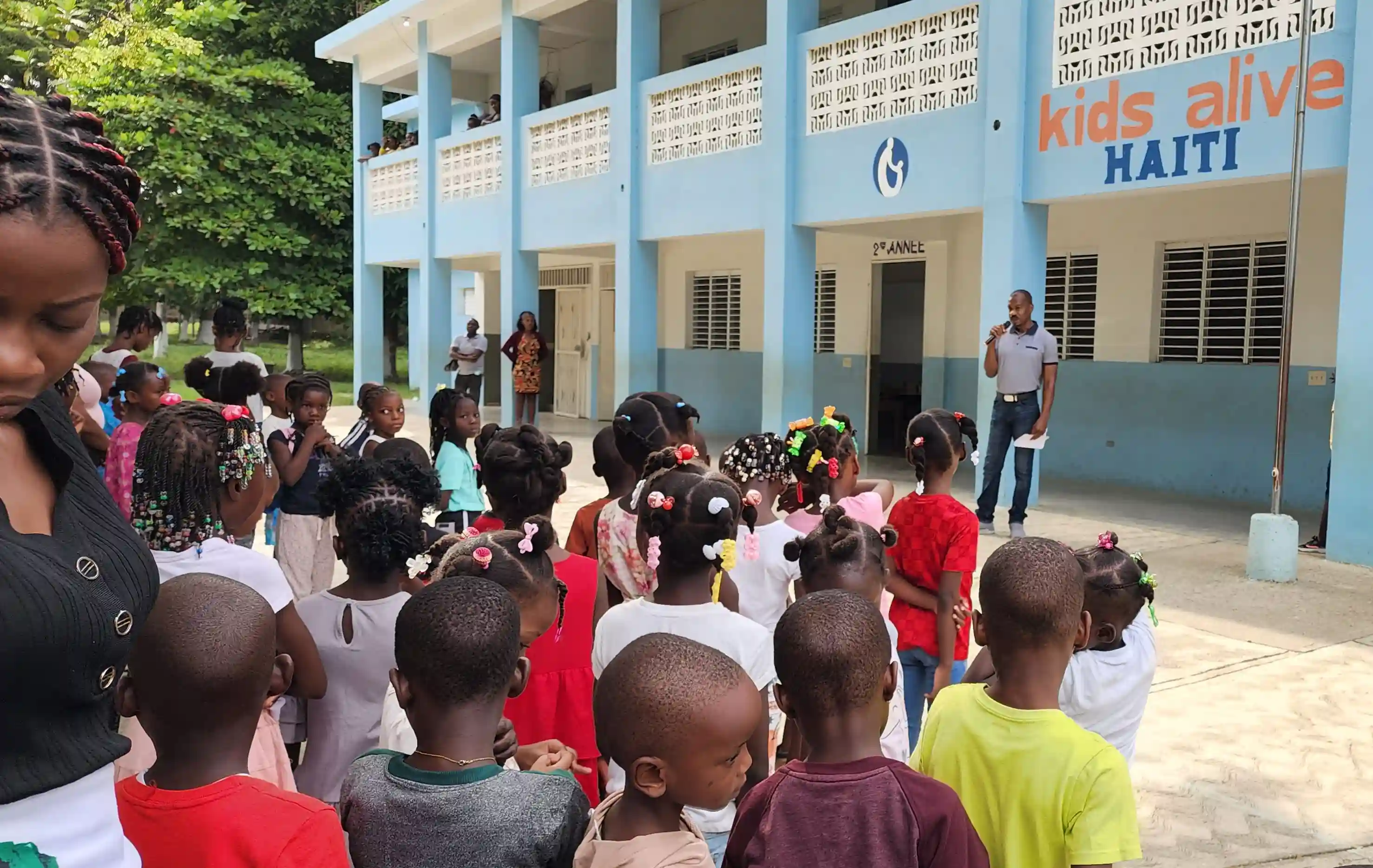 Classes of students standing outside for assembly at Kids Alive Haiti School.