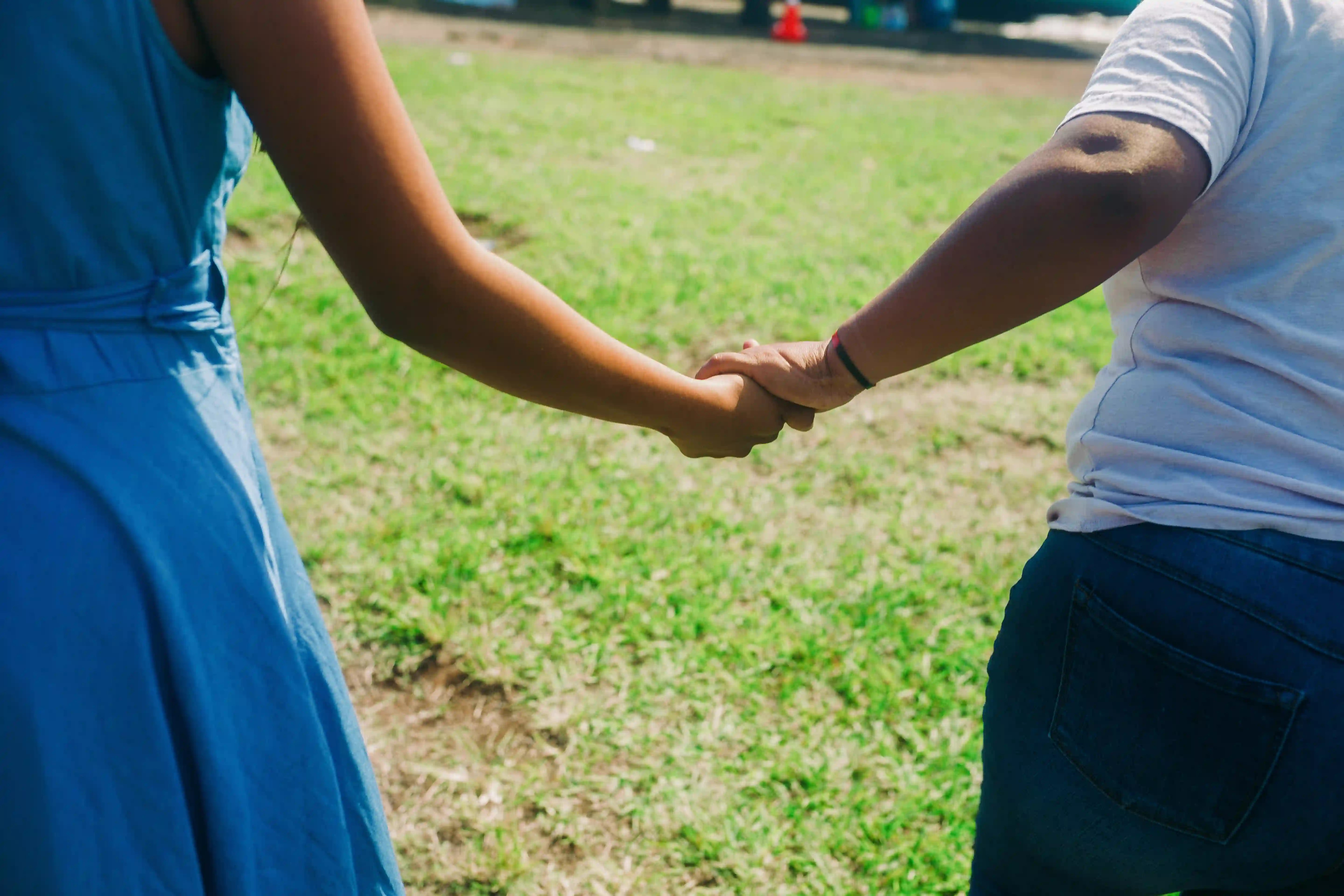 A girl and her mother holding hands.