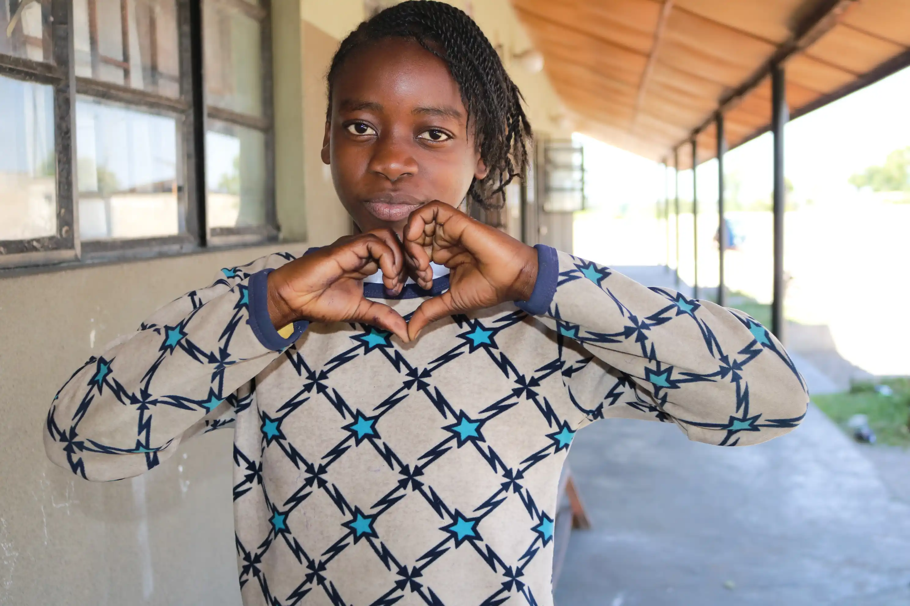 Zangi standing outside of her classroom at Kids Alive Academy Zambia and can boldly express that she is God's masterpiece.