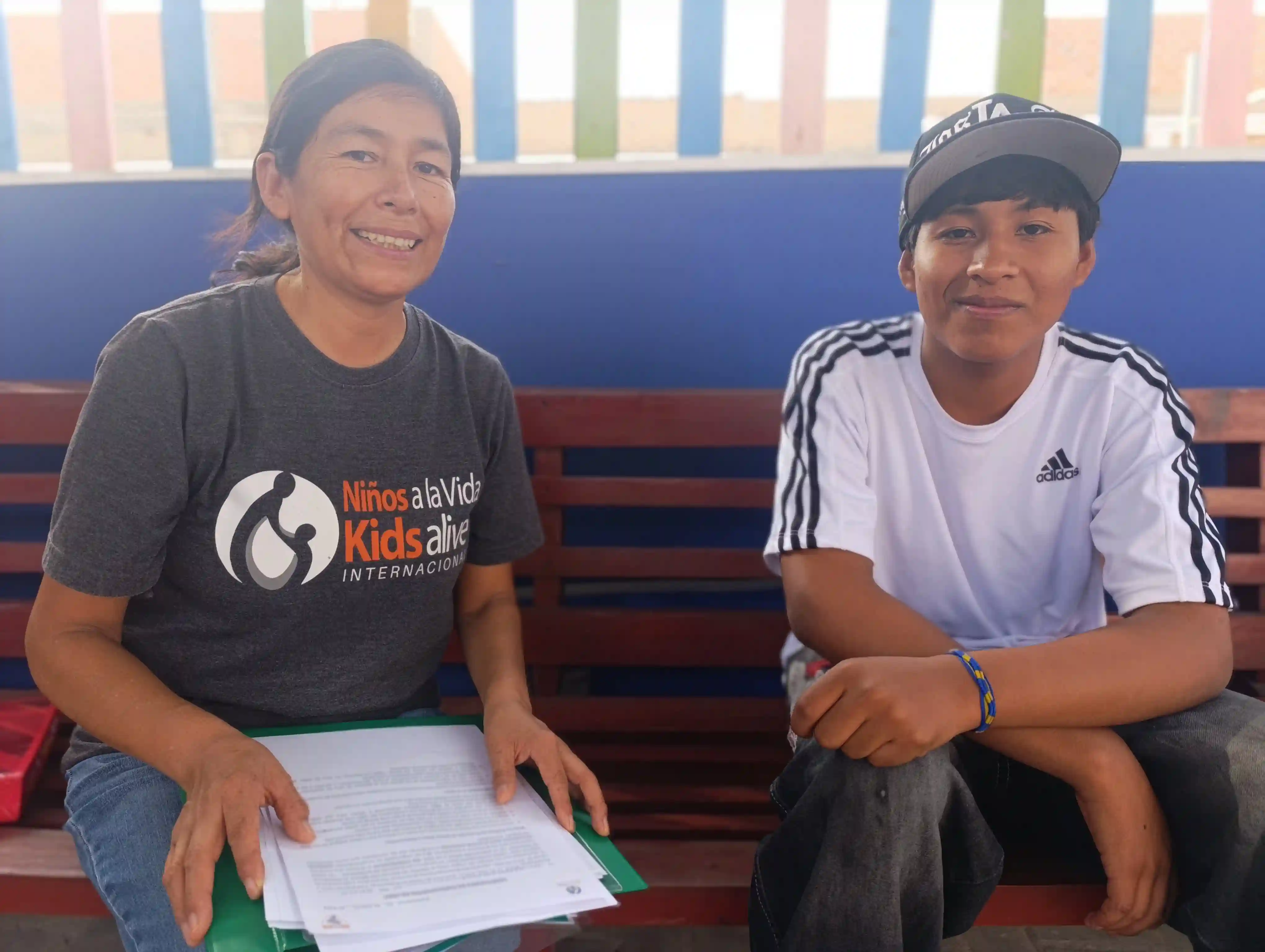 Hugo sitting with his teacher, Ms. Jenny, who believed in his potential.