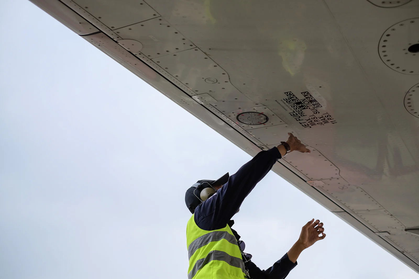 Technicien inspectant le dessous de l'aile d'un avion