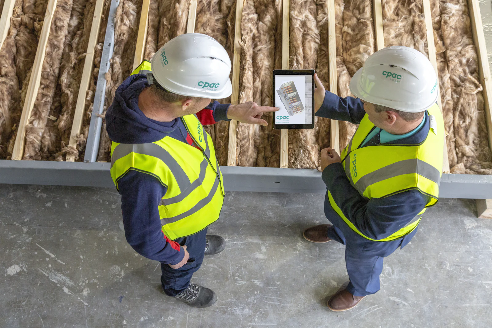 Deux techniciens consultant une tablette sur un chantier