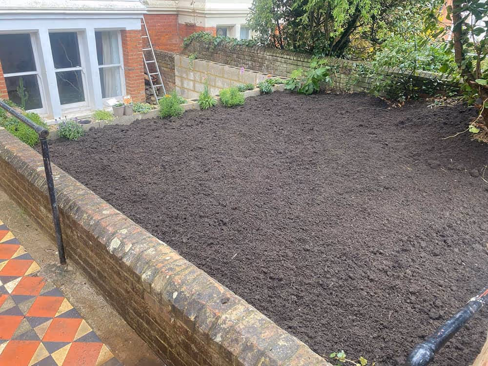 A garden with a brick wall and a garden bed.