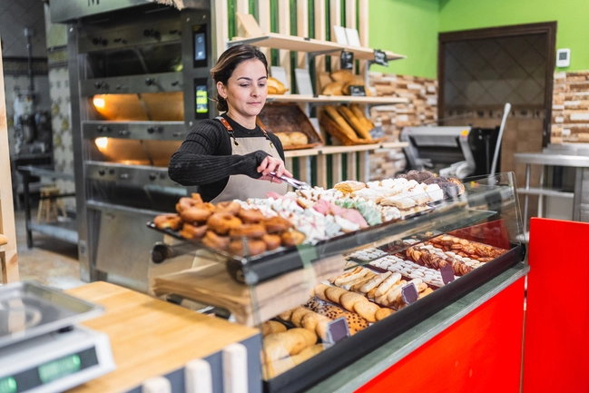 Une pâtissière prépare les gâteaux et viennoiseries qu'elle s'apprête à vendre dans sa boutique et dans son distributeur automatique de gâteaux.
