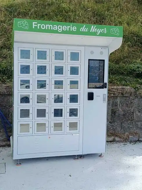 Photo du distributeur multiproduits de la Fromagerie du Noyer, avec son abri minimaliste et sa borne de commande tactile.
