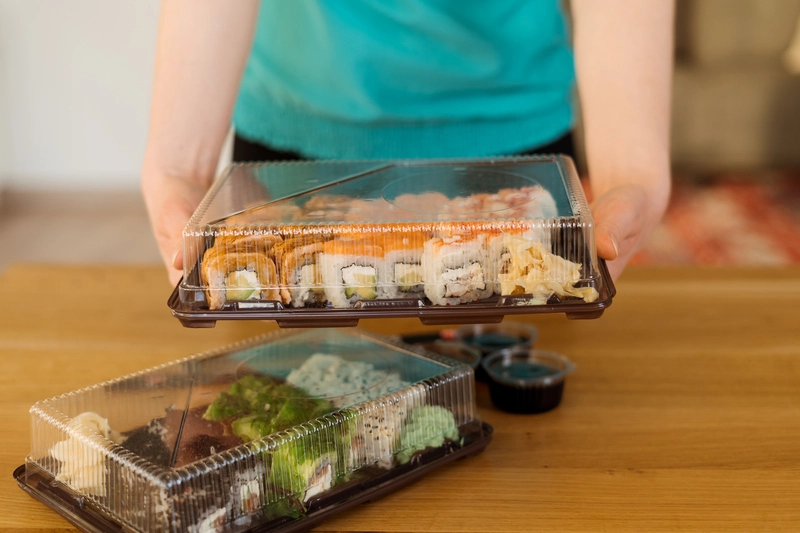Un traiteur conditionne ses plats préparés dans des boîtes alimentaires afin de les vendre en distributeur réfrigéré.