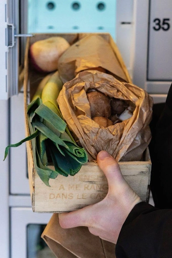 Un exploitant agricole place une cagette de légumes dans un casier réfrigéré.