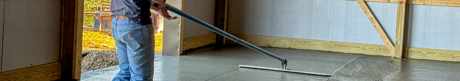 Concrete worker leveling concrete in a barn