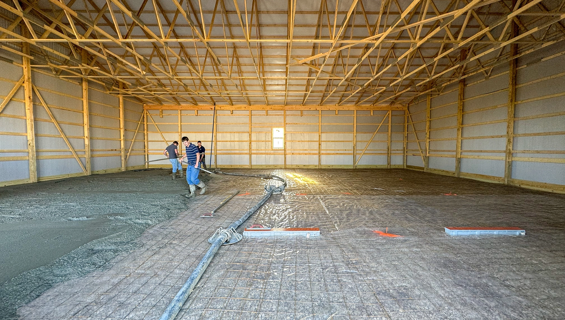 Workers pouring a reinforced concrete floor inside a large building