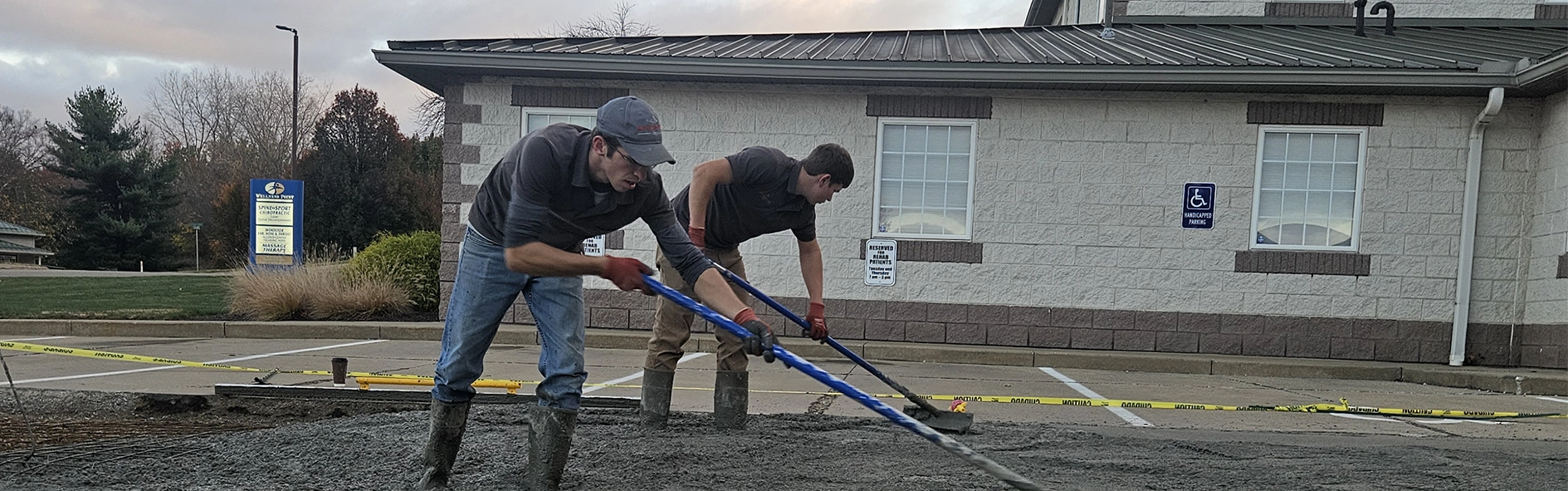 concrete workers leveling freshly poured concrete in a parking lot