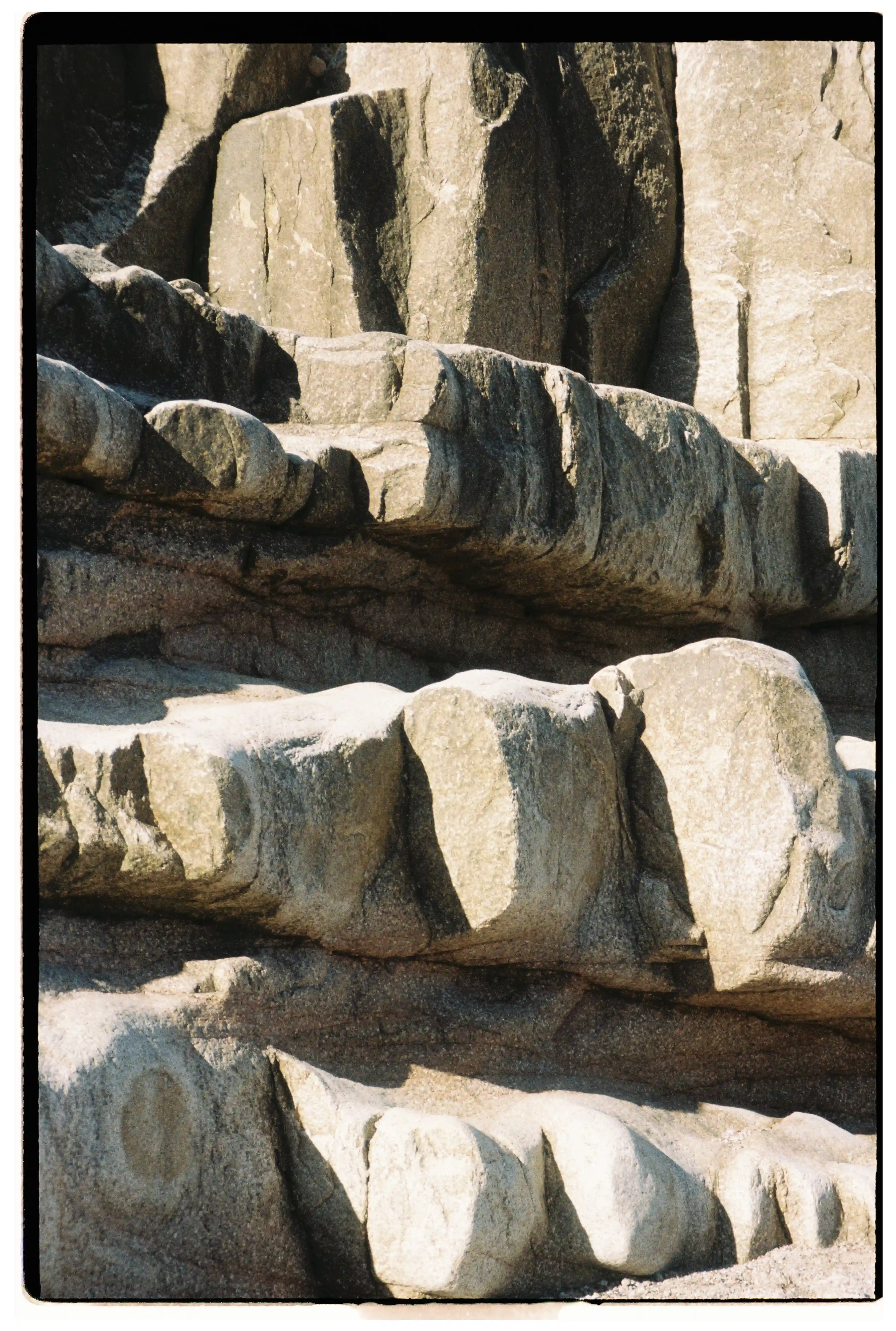 Stries naturelles dans la roche polies par la mer, révélées par un jeu d’ombre et de lumière.