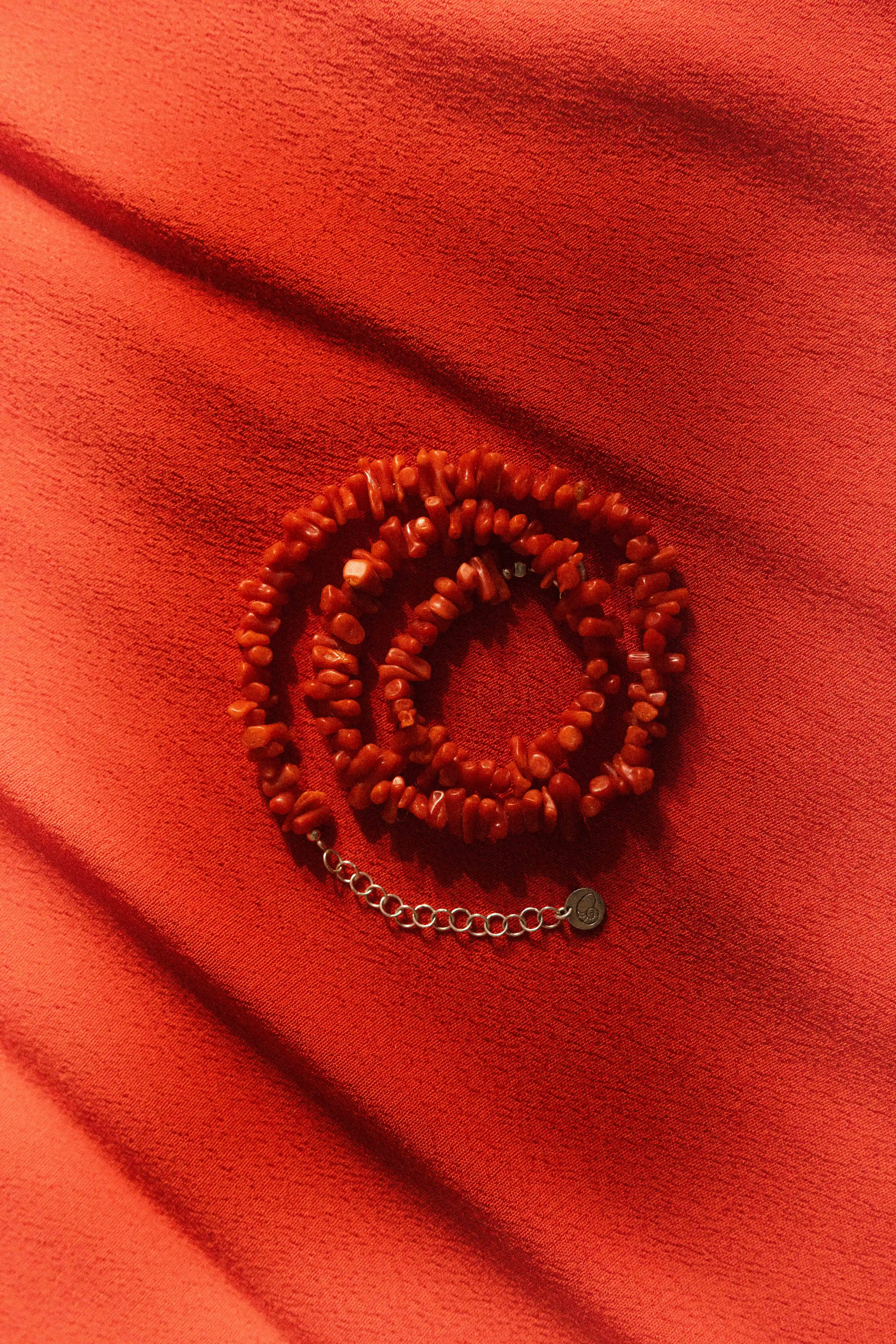 Collier type ras le cou, en corail rouge de la maison du corail à Ajaccio en Corse, sur fond rouge.