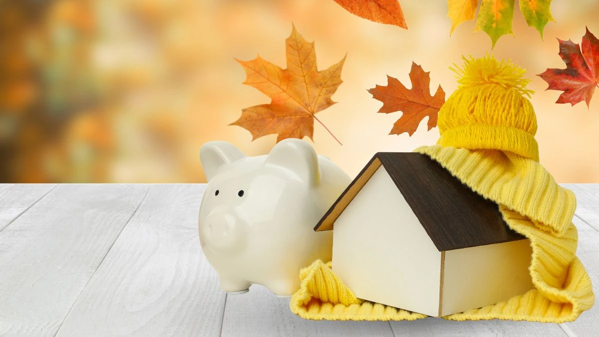 Illustration montrant une tirelire en forme de cochon, une maison enveloppée d’une écharpe et des feuilles d’automne qui tombent.
