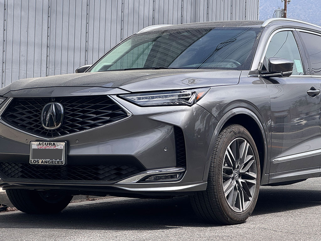 Front-end collision damage on a grey Acura MDX featuring crushed hood, broken headlight, and exposed structural components.